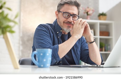 Gepflegter Mann, der online arbeitet, mit Laptop-Computer zu Hause sitzend am Schreibtisch. Home office, browsing internet, studienraum. Porträt des reifen Alters, mittleren Alters, mittleren erwachsenen Menschen in den 50ern.