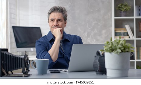 Gepflegter Mann, der online arbeitet, mit Laptop-Computer zu Hause sitzend am Schreibtisch. Geschäftsmann zu Hause, Surfen im Internet. Porträt des reifen Alters, mittleren Alters, mittleren erwachsenen Menschen in den 50ern.