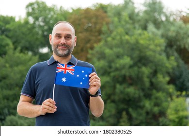 Bearded middle-aged man with the flag of Australia on a background of green trees. - Powered by Shutterstock