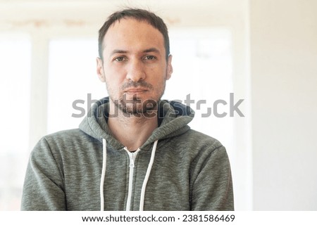 Bearded middle-aged man looking at camera with a serious expression in a close up head and shoulders portrait