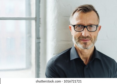 Bearded middle-aged man wearing glasses looking at camera with a serious expression in a close up head and shoulders portrait - Shutterstock ID 1016721721