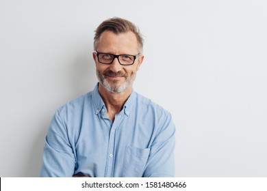 Homem barbudo de meia-idade usando óculos posando sobre um fundo branco de estúdio com espaço de cópia olhando para a câmera com um sorriso amigável