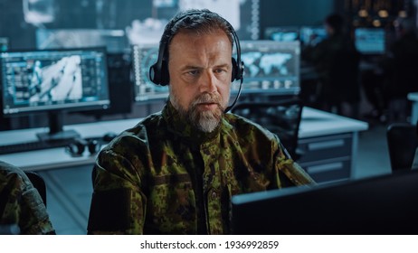 Bearded Military Surveillance Officer In Headset Working In A Central Office Hub For Cyber Operations, Control And Monitoring For Managing National Security, Technology And Army Communications.