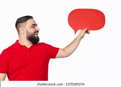 Bearded Overweight Man In Red T-shirt Smiling And Holding Empty Speech Balloon While Standing Against White Background