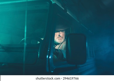 Bearded Senior Guy Looking At The Side Mirror To See The Rear View While Driving His Vehicle In The Middle Of The Night.