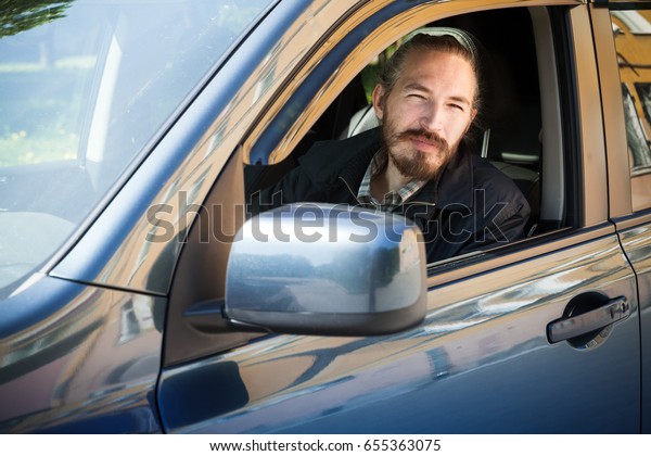 Bearded serious Asian\
man, driver of modern Japanese crossover suv car, outdoor portrait\
in open car window