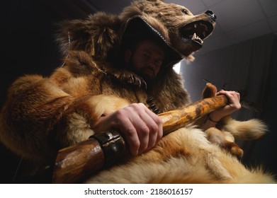 Bearded Serious Man Sits In A Suit In The Skin Of A Dead Bear With An Ax In His Hands