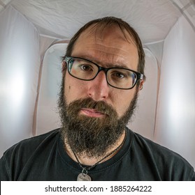 A bearded seriously looking man with black glasses