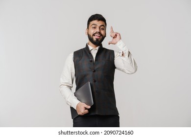 Bearded South Asian Man Pointing Finger Upward While Posing With Laptop Isolated Over White Wall
