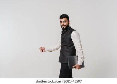 Bearded South Asian Man Wearing Vest Posing With Laptop Isolated Over White Wall