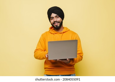 Bearded South Asian Man Wearing Turban Using Laptop Isolated Over Yellow Wall