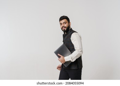 Bearded South Asian Man Wearing Vest Posing With Laptop Isolated Over White Wall