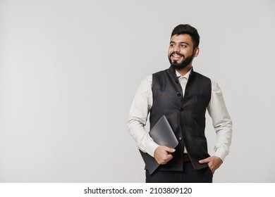 Bearded South Asian Man Wearing Vest Laughing While Posing With Laptop Isolated Over White Wall