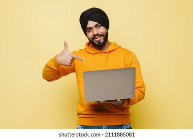 Bearded South Asian Man Wearing Turban Pointing Finger At His Laptop Isolated Over Yellow Wall