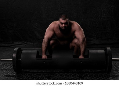 The Bearded Strongman Crouched Down And Prepares To Lift A Large Metal Log