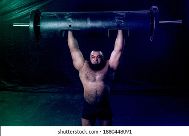 A Bearded Strongman Raised A Large Metal Log Above Him