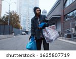 Bearded tramp man with bag on city street