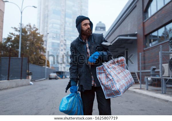 Bearded tramp man with\
bag on city street