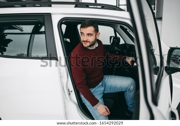 Bearded\
white brunette man sitting in white car in\
salon