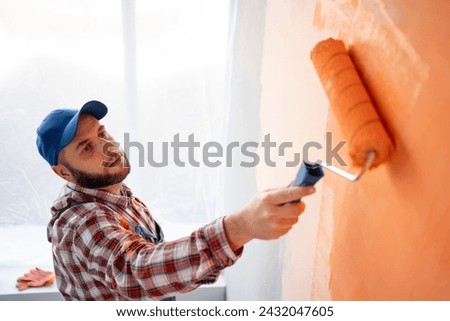Bearded worker painting a wall with a paint roller, top view. Home renovation and redecoration concept. Copy space [[stock_photo]] © 