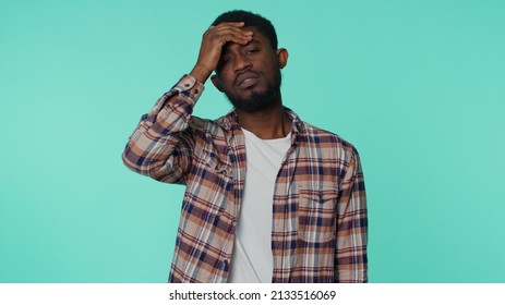 Bearded Young African American Man Rubbing Temples To Cure Headache Problem, Suffering From Tension And Migaine, Stress, Grimacing In Pain, High Blood Pressure Isolated Alone On Blue Wall Background