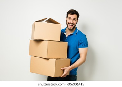 bearded young man in blue shirt carrying three carton boxes on a white wall