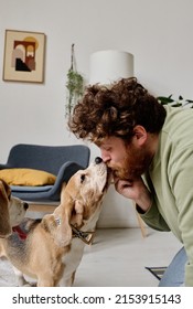 Bearded Young Man Loving His Dog Very Much, He Kissing And Pampering His Pet