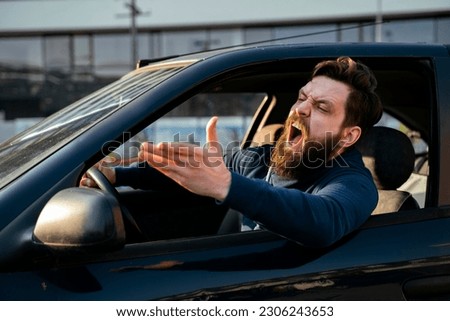 Bearded young man road raging , yelling from the car closeup shot
