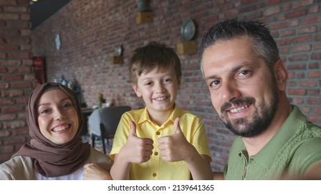 Bearded Young Man With Turbaned Wife And Son Talking To Loved Ones On Video Call With Mobile Phone Camera. Happy Family Waving To Their Loved Ones In The Photo.Frontal Phone Camera View.