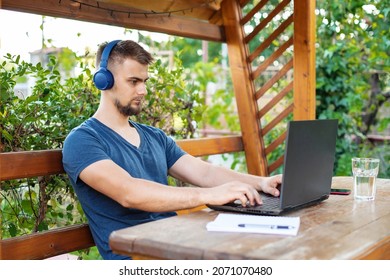 A bearded young man is using computer laptop for working at outdoors, working freelance project online outdoors at home, handsome student studying, learning, online education, freelancer - Shutterstock ID 2071070480