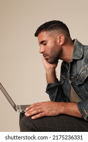 Bearded young man using laptop while posing indoor. Vertical mock-up.