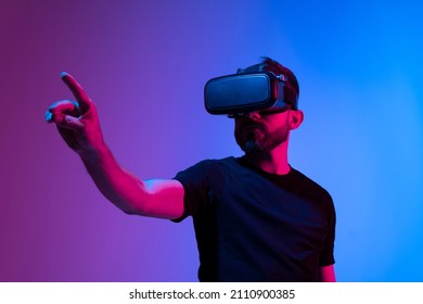 Bearded young man in virtual reality glasses in the studio with blue and pink light. - Shutterstock ID 2110900385