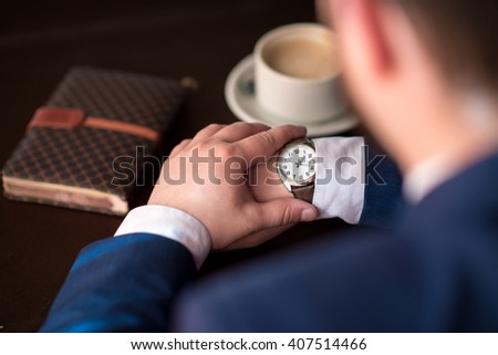 Bearded young successful businessman punctual keeps track of time, a man in a suit waits for the client