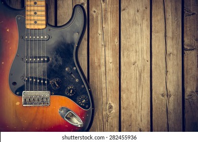 A beat up and dirty vintage electric guitar body against a natural wood-grain boards background. - Powered by Shutterstock