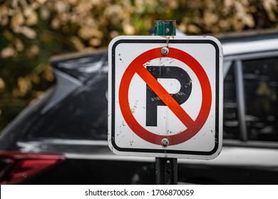 Beat Up No Parking Sign With A Car In The Backdrop