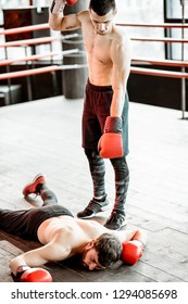 Beaten Boxer Lying Knocked Out On The Boxing Ring With Strong Man Winner Above