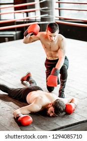 Beaten Boxer Lying Knocked Out On The Boxing Ring With Strong Man Winner Above