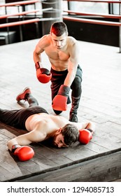 Beaten Boxer Lying Knocked Out On The Boxing Ring With Strong Man Winner Above