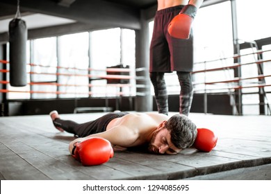 Beaten boxer lying on the floor during a boxing battle, having a knockdown on the boxing ring - Powered by Shutterstock