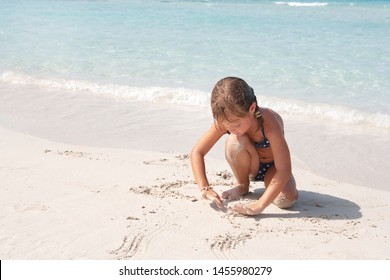 Beatiful Child Playing With Sand On Beach Shore, Writing On Sand In Bikini, Summer Holiday Outdoors. Kid Games Childhood Fun, Sunny Wet Vacation Leisure Recreation Lifestyle, Coastal Exterior.