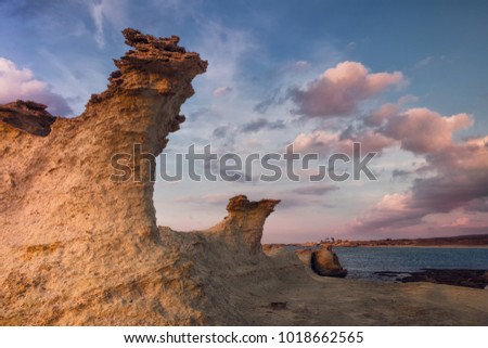 Beatiful Cyprus sunset on the desert empty rocky coast with strange fiqures at the Halk beach