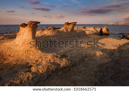 Beatiful Cyprus sunset on the desert empty rocky coast with strange fiqures at the Halk beach