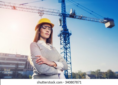 beatiful woman engineer is standing serious in front of a crane - Powered by Shutterstock