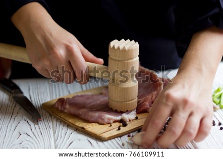 beating raw steak with meat mallet in kitchen