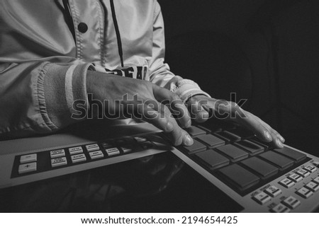 Beatmaker producing some beats with a drum machine in his home studio. Hip hop composer. On mpc DJ plays the beats live on the pad controller of digital audio equipment. Rap music.