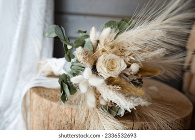 Beatyful dried bridal bouquet in natural boho style on rustic wood. Sustainable wedding decoration. Floral still life with wedding dress. - Powered by Shutterstock