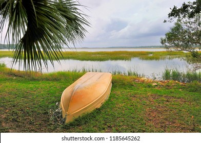 BEAUFORT, SOUTH CAROLINA - October 8, 2008: An Overturned Boat Lies Beneath A Palmetto Tree Along The Banks Of A Marsh Inlet As Stormy Weather Approaches From The Atlantic.