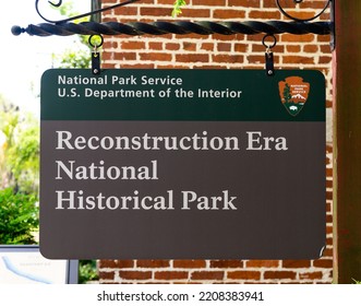 Beaufort, South Carolina, USA- April 30, 2021: Reconstruction Era National Historical Park Sign Is Hanging From A Metal Post In Front Of A Red, Brick Wall.