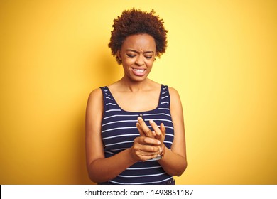 Beauitul african american woman wearing summer t-shirt over isolated yellow background Suffering pain on hands and fingers, arthritis inflammation
