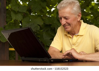 Beauteous Older Man Sitting At A Table At Home On The Veranda